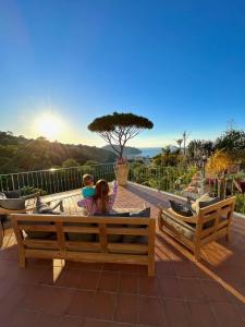 a girl and boy sitting on a bench on a patio at Resort Villa Flavio in Ischia