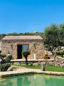 a stone house with a pond in front of it at Villa Case Vecchie in La Murta