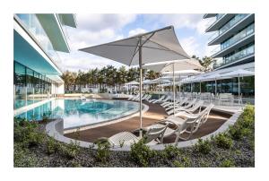 Una piscina con sillas y sombrillas al lado de un edificio. en Wave Holiday Club, en Międzyzdroje