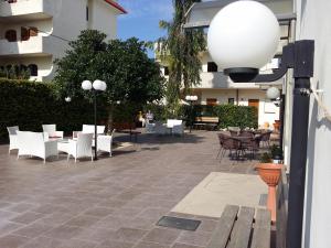 un patio avec des chaises et des tables blanches et un bâtiment dans l'établissement La Tana del Lupo, à Monteiasi
