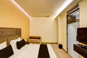 a bedroom with a bed and a tv and a chair at Super Townhouse Rohini Near Paschim Vihar Metro Station in New Delhi