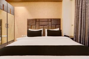 a bedroom with a large bed with a wooden headboard at Super Townhouse Rohini Near Paschim Vihar Metro Station in New Delhi
