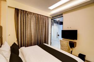a hotel room with a bed and a tv at Super Townhouse Rohini Near Paschim Vihar Metro Station in New Delhi