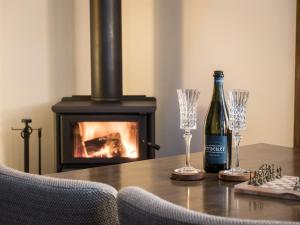 a bottle of wine and two glasses on a table with a fireplace at Serenity House Pemberton & Wellness Spa in Pemberton
