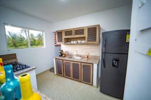 La cuisine est équipée d'un réfrigérateur noir et d'un évier. dans l'établissement Cabaña Villa July, à Moñitos