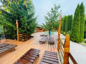 a group of benches on a wooden deck with trees at Pensiunea Ioana in Borşa +56 photos