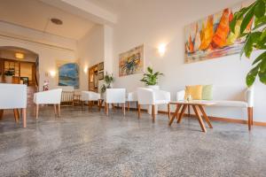 uma sala de espera com cadeiras e mesas brancas em Hotel Il Gabbiano em Alghero