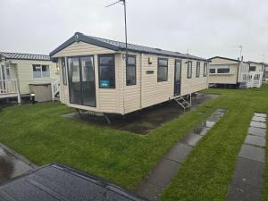 a tiny house sitting on top of a yard at Lyons robin hood caravan 43SW in Rhyl
