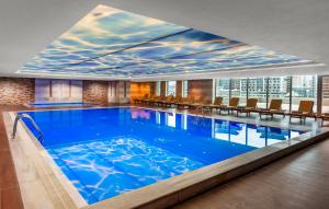 a large swimming pool in a hotel with a large window at Kaya İstanbul Fair & Convention in Istanbul