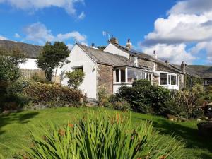 a white house with a garden in front of it at 4 Bed in Keswick 86250 in Threlkeld