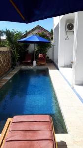 a swimming pool with an umbrella and chairs and a table at Spear Villa in Bumbang