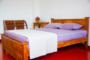 a bedroom with a wooden bed with purple pillows at SkyAvenue Guest House in Kadawata
