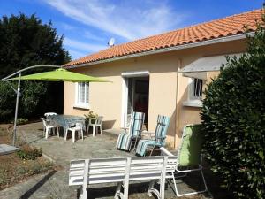a patio with a table and chairs and an umbrella at Maison confortable à Saint-Hilaire-de-Riez avec jardin clôturé in Saint-Hilaire-de-Riez