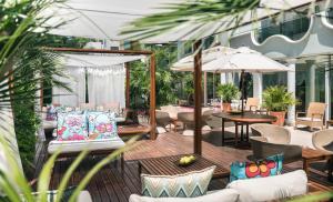 an outdoor patio with chairs and tables and umbrellas at Hotel De Londres in Rimini