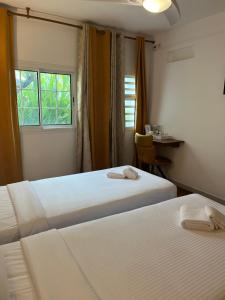 two beds in a room with a desk and a window at Hôtel Les Embruns Du Baril in Basse Vallée