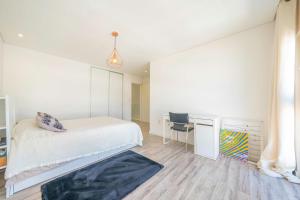 una camera da letto bianca con un letto e una scrivania di Black Pool House just 10 minutes away from the beach a Amora Altre 33 foto