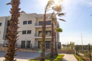 a white building with palm trees in front of it at Apartamentos Arenal 2 in Jávea