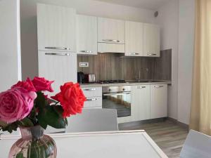 a kitchen with red roses in a vase on a table at Appartamento Burantinu in Alghero