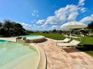 a swimming pool with two chairs and an umbrella and an umbrella at Appartamento Burantinu in Alghero