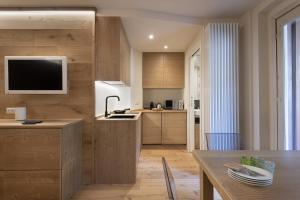 cocina con armarios de madera y TV en la pared en Bijoux Sozzine, en Ponte di Legno