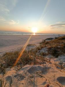 a sunset on a beach with a chair in the sand at Sea Sand apartment in Liepāja