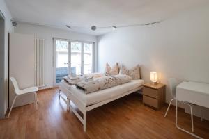 a white bedroom with a bed and a desk at Ferienhaus Rütiboda bis 17 Personen in Davos