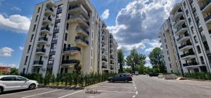 two tall buildings with cars parked in a parking lot at Appartment Chindia Lake in Târgovişte