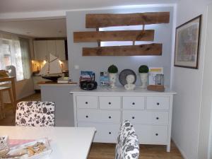 a white dresser in a living room with a kitchen at Ferienhaus Dieknuest, 15172 in Leer +13 photos