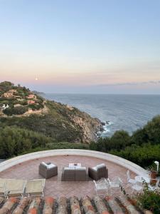 een terras met een tafel en stoelen en de oceaan bij Villa Bianca, piscina e panorama in Torre delle Stelle