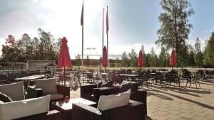 un patio avec des tables, des chaises et des parasols rouges dans l'établissement Piteå Golfhotell, à Piteå