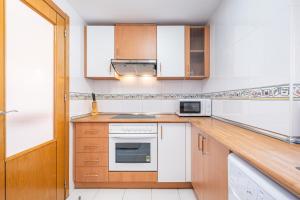 a kitchen with white appliances and wooden cabinets at Acintur 13-A Apartment Levante Beach-Old Town in Benidorm
