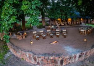 a fire pit with tables and chairs in a park at Hideaways Bumbusi Wilderness Camp, Hwange in Hwange