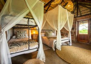 a bedroom with two beds with mosquito netting at Hideaways Bumbusi Wilderness Camp, Hwange in Hwange
