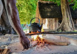 a person is holding a pot over a fire at Hideaways Bumbusi Wilderness Camp, Hwange in Hwange
