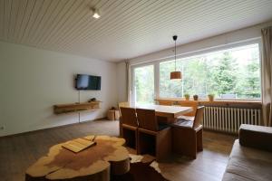 姆根布朗Fewo "am Mühlenbach" im Haus Hohfels, 2 Schlafzimmer, Todtnau-Muggenbrunn, Hochschwarzwald的带桌子和大窗户的客厅