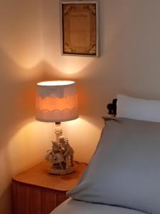 a lamp on a night stand next to a bed at Bed and Breakfast Papillon in Perledo