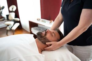 uma mulher a cortar o cabelo de um homem numa cama em Spa & Wellness Hotel Olympia Marienbad em Mariánské Lázně