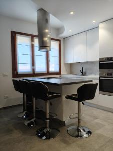a kitchen with a island with black counter chairs at HappyKids bb Venice in Campalto