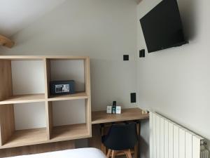 a room with a desk and a tv on a wall at Hôtel-Restaurant Logis l'Aubrac Laguiole in Laguiole