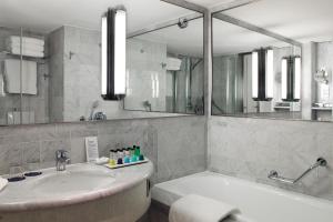 a bathroom with a tub and a sink and a mirror at Sheraton Paris Charles de Gaulle Airport Hotel in Roissy-en-France