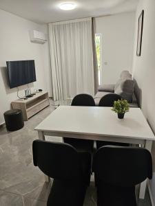 a living room with a white table and chairs at Vrexi Apartment - By IMH Travel & Tours in Paphos City