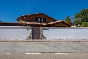 una casa con una pared blanca y un garaje en La Dehesa y Dehesa2 de Toledo en Cobisa