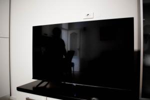 a person is sitting in a chair behind a television at Apartman Agata,Osijek, self check-in in Osijek