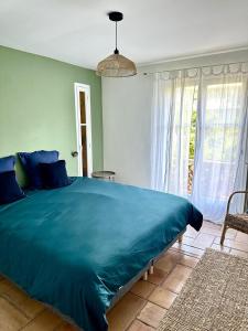a bedroom with a large blue bed and a window at Casa sardine in Cassis