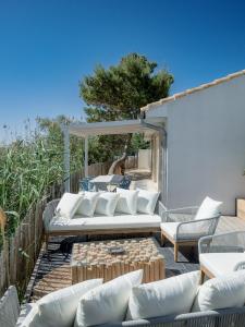 a patio with white couches and a table and aented at La Perle Rose Villa Standing 5 étoiles avec piscine jacuzzi et superbe vue in Aigues-Mortes +205 photos