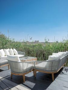 three white chairs with pillows on a patio at La Perle Rose Villa Standing 5 étoiles avec piscine jacuzzi et superbe vue in Aigues-Mortes