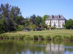 a large house on a hill next to a body of water at Des alleux in Saint-Ouen-des-Alleux