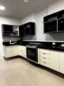 a kitchen with white cabinets and black appliances at Casa Paraiso de Praia in Porto Seguro