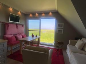 a living room with a couch and a table and a window at Ferienwohnung Feskerdam 28 OG in Morsum