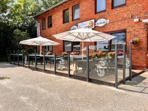 a restaurant with tables and umbrellas in front of a building at Nordseehotel Eymers in Nordholz